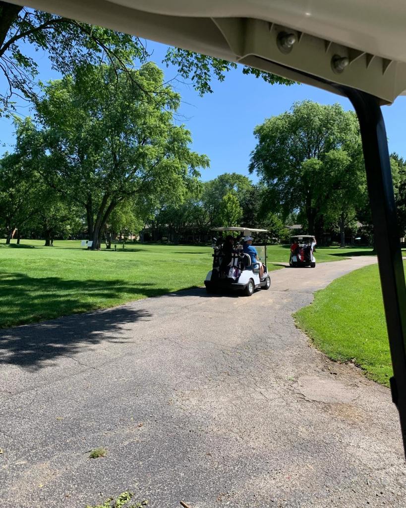 Golfers on golf cart on golf course cart path